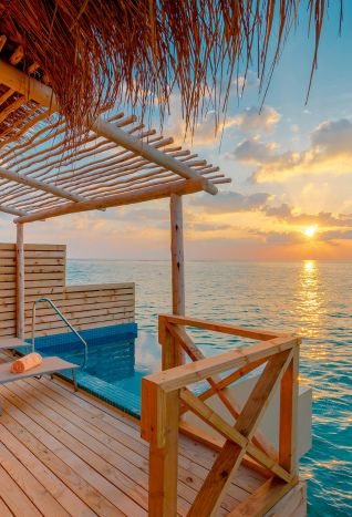 a sunset view on the deck of a private over the water bungalow