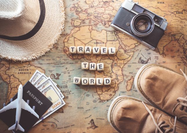 map on a desk with travel images and words spelling out: Travel the world.
