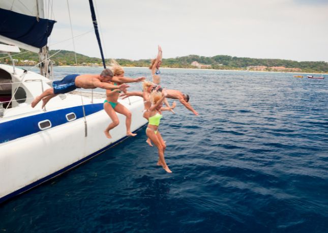 people jumping of a boat into the Caribbean water