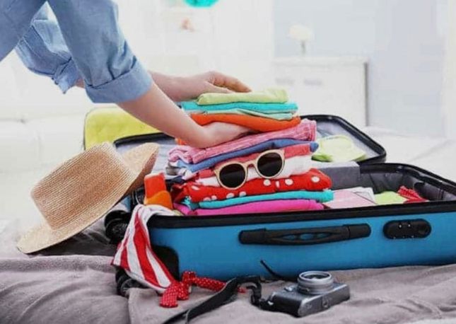 Woman's arm packing a suitcase for a trip